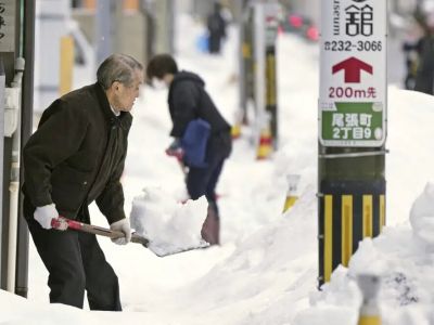 Жители Канадзавы убирают снег с тротуара, 24 декабря 2022 года. Фото: Kyodo News via AP
