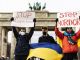 Участники акции солидарности с Украиной стоят у Бранденбургских ворот в Берлине с плакатами 